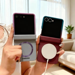 May include: Two Samsung phone cases are shown, one grey and one burgundy. The grey case has a purple accent and a circular design, while the burgundy case has a white circular charger. Both cases are open, revealing the phone screens.
