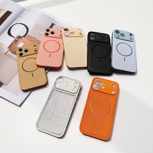 Pode incluir: Uma coleção de capas de telemóvel coloridas em várias tonalidades, incluindo bege, rosa, bege, preto, azul claro, prateado e laranja. Cada capa apresenta um design circular e um recorte para a câmara. As capas estão dispostas numa superfície branca.