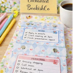 Può includere: Un blocco note a fantasia floreale e a rombi blu e bianchi, con elenchi di attività sotto le voci «WORK» e «PERSONAL». Il blocco note è tenuto insieme da bottoni a pressione argentati. Il blocco note riporta il testo «Enchanted BookishCo».