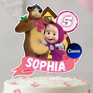 Op de afbeelding: Een taarttopper met de tekenfilmfiguren Masja en de Beer, met het nummer 5 en de naam "Sophia" op een roze banner. De topper is geplaatst op een witte taart versierd met roze bloemen.