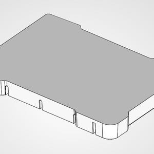 May include: A rectangular, gray object with a rounded corner and several rectangular cutouts along the sides. The object has a flat top surface and appears to be made of a solid material. The design is simple and modern.