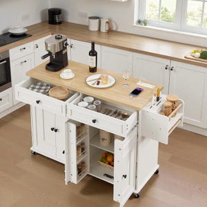 May include: White kitchen island with a light wood countertop. Features include drawers, cabinets, and a side rack. A coffee maker, wine bottle, and food items are on the countertop. The island has wheels for mobility.