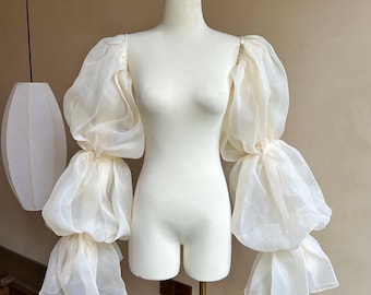 Vestido de organza transparente con hombros descubiertos y mangas abullonadas desmontables en capas.