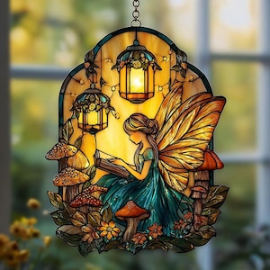 May include: Stained glass panel featuring a fairy reading a book, surrounded by mushrooms and flowers. The fairy has golden wings and wears a teal dress. The panel includes three lanterns and is suspended by a chain.