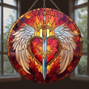 Puede incluir: Vidriera redonda que representa una espada que atraviesa un corazón, flanqueada por alas. El diseño incorpora tonos rojos, naranjas y amarillos, con una espada y un contorno de corazón dorados. Las alas son blancas y doradas, y el fondo se asemeja a llamas.