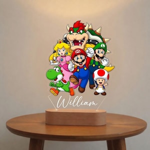 May include: A colourful acrylic night light featuring characters from the Super Mario video game series, including Mario, Luigi, Princess Peach, Yoshi, and Bowser. The base is made of wood, and the name "William" is written on the acrylic.