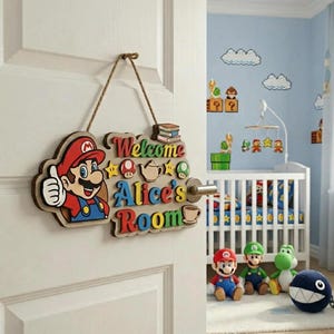 May include: A wooden hanging door sign featuring a colourful cutout of Mario giving a thumbs up. The sign displays the text "Welcome Alice's Room" in multi-coloured letters, accented with small wooden icons of mushrooms, stars, a teapot, a cup, and books.