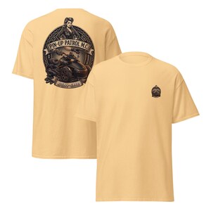 Puede incluir: Dos camisetas amarillo claro. Una camiseta presenta un gran gr&aacute;fico en la espalda con una pin-up, una motocicleta y el texto "PIN-UP PATROL M.C." y "CAN-AM". La otra camiseta tiene un peque&ntilde;o gr&aacute;fico en la parte delantera.