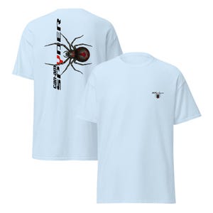 Pode incluir: T-shirts azul claro com um desenho de aranha preta e vermelha. Uma camisa tem um grande desenho de aranha com o texto "Can-Am Spyder", enquanto a outra tem um logotipo de aranha menor. As camisas s&atilde;o feitas de um material macio.