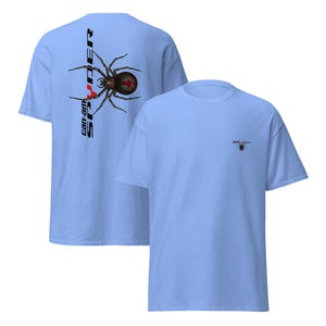 Pode incluir: T-shirts azul claro com um desenho de aranha. Uma camisa apresenta um grande desenho de aranha com o texto "Can-am Spyder" na vertical. A outra camisa tem um desenho de aranha menor no peito.