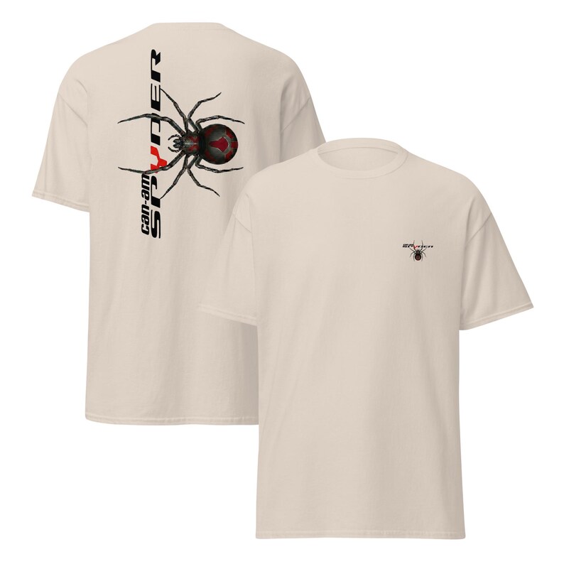 Pode incluir: Duas camisetas bege. Uma apresenta um gr&aacute;fico de aranha preta e vermelha com o texto "can-am SPYDER" verticalmente no lado esquerdo. A outra camisa tem um gr&aacute;fico de aranha menor.