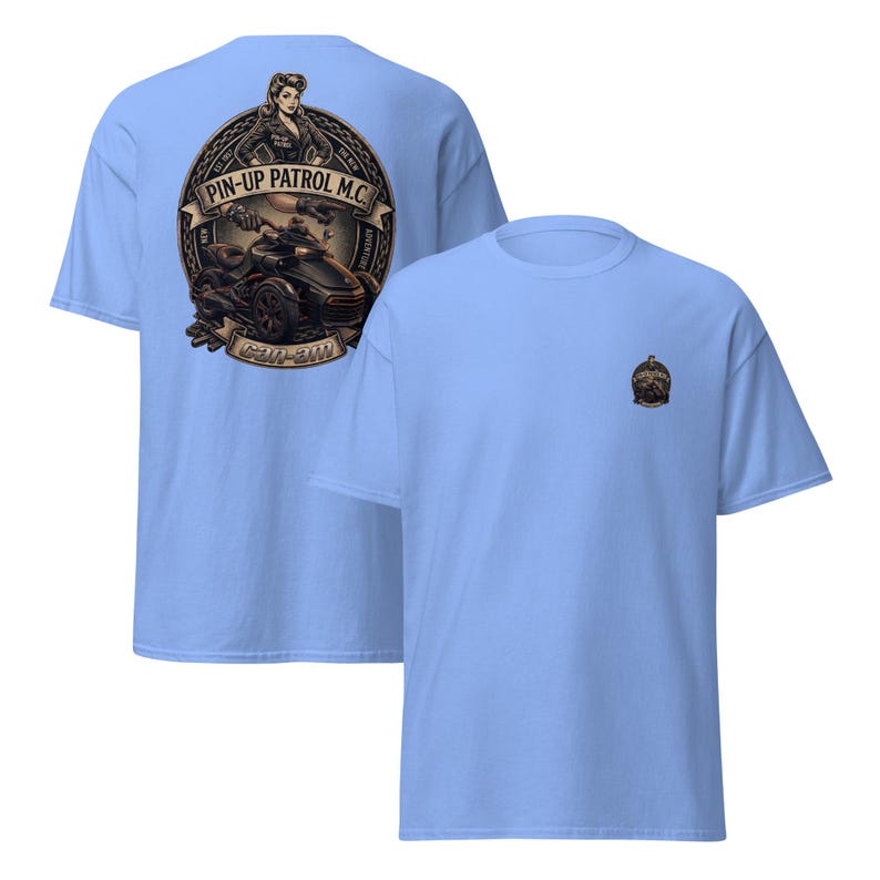 Puede incluir: Camisetas de color azul claro con un dise&ntilde;o gr&aacute;fico. Una camiseta presenta un gran emblema circular con una pin-up, una motocicleta y el texto "PIN-UP PATROL M.C." y "CAN-AM". La otra camiseta tiene un emblema m&aacute;s peque&ntilde;o.