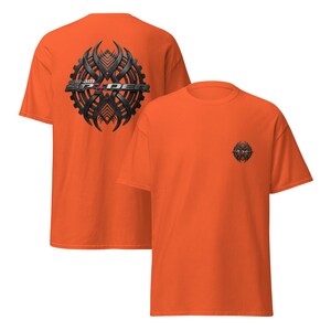 Peut inclure: T-shirt orange vif avec un motif graphique noir et gris &agrave; l'avant et &agrave; l'arri&egrave;re. Le dos du t-shirt porte l'inscription "I am SPYDER" en argent et noir. L'avant du t-shirt pr&eacute;sente une version plus petite du m&ecirc;me motif.