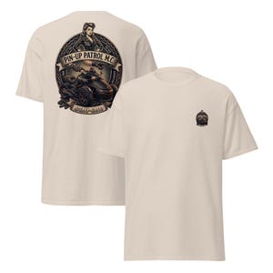 Puede incluir: Dos camisetas color crema. Una presenta un gran gr&aacute;fico en la espalda con una pin-up, una motocicleta y el texto "PIN-UP PATROL M.C." y "CAN-AM". La otra camiseta tiene un gr&aacute;fico m&aacute;s peque&ntilde;o en la parte delantera.