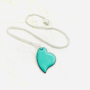 May include: A silver chain necklace with a teal blue heart pendant.