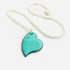 May include: A silver chain necklace with a teal blue heart pendant.