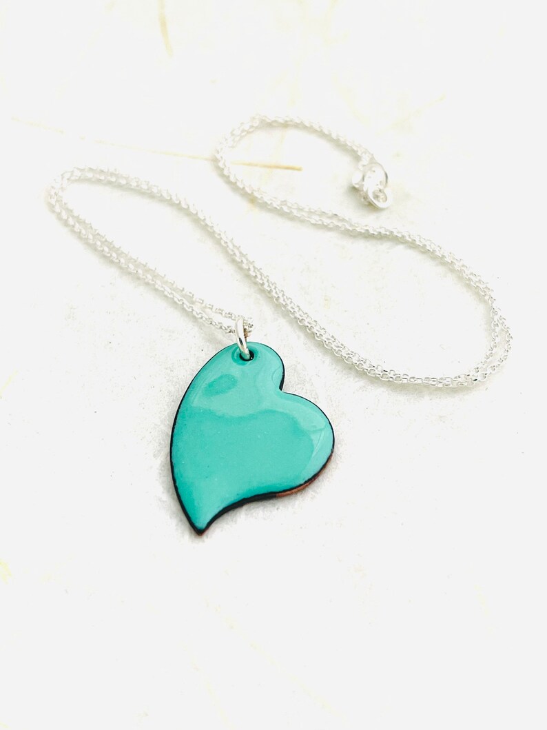 May include: A silver chain necklace with a teal blue heart pendant.