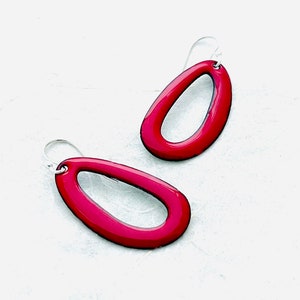 May include: A pair of red enamel earrings with a simple oval shape and silver hooks.