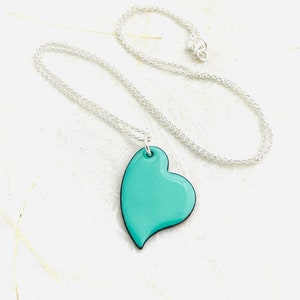 May include: A silver chain necklace with a turquoise heart pendant.