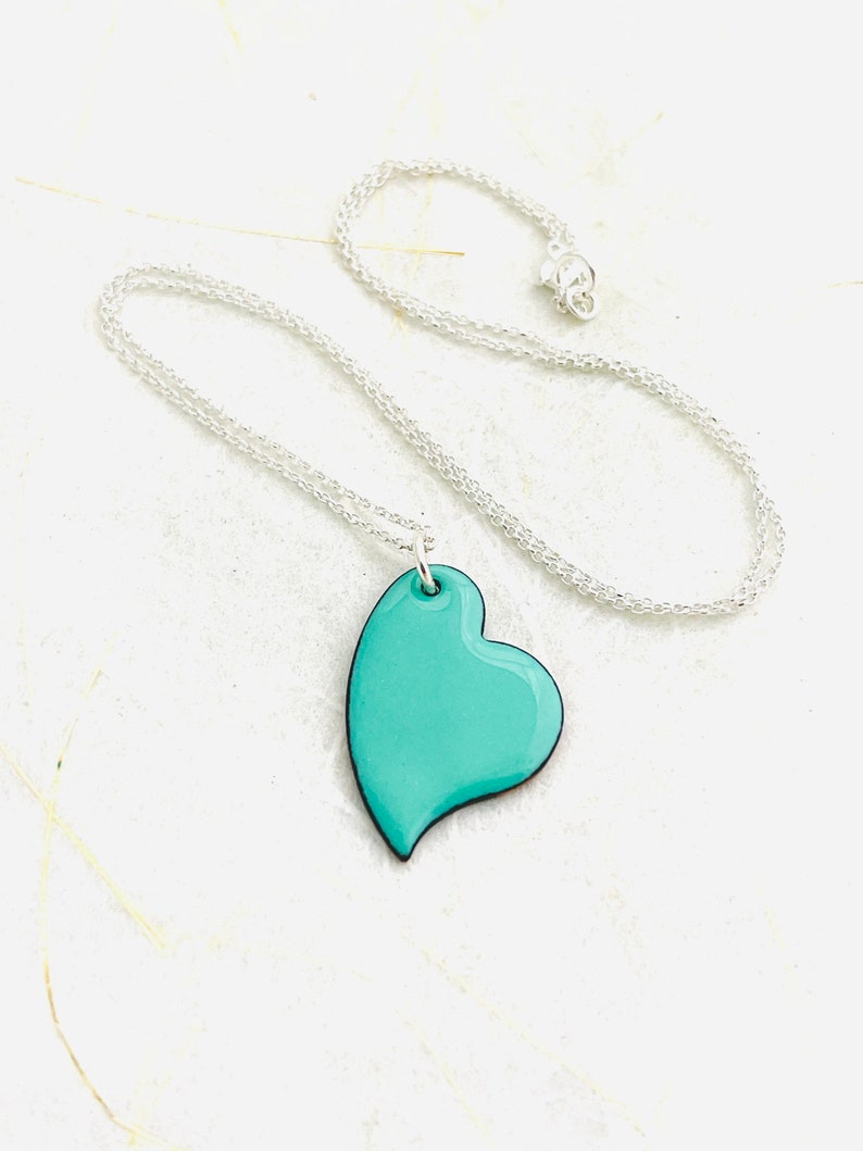 May include: A silver chain necklace with a turquoise heart pendant.
