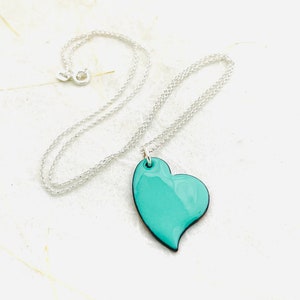 May include: A silver chain necklace with a turquoise heart pendant.