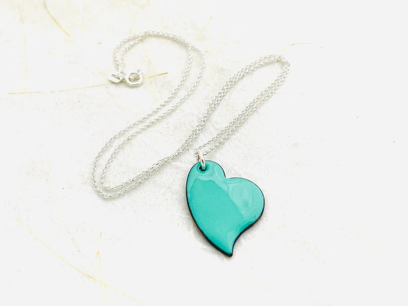 May include: A silver chain necklace with a turquoise heart pendant.