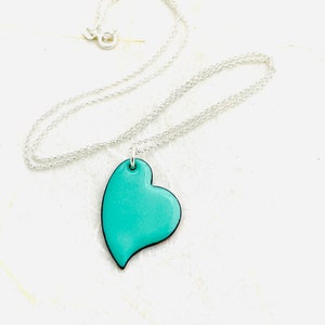 May include: A silver chain necklace with a turquoise blue heart pendant.