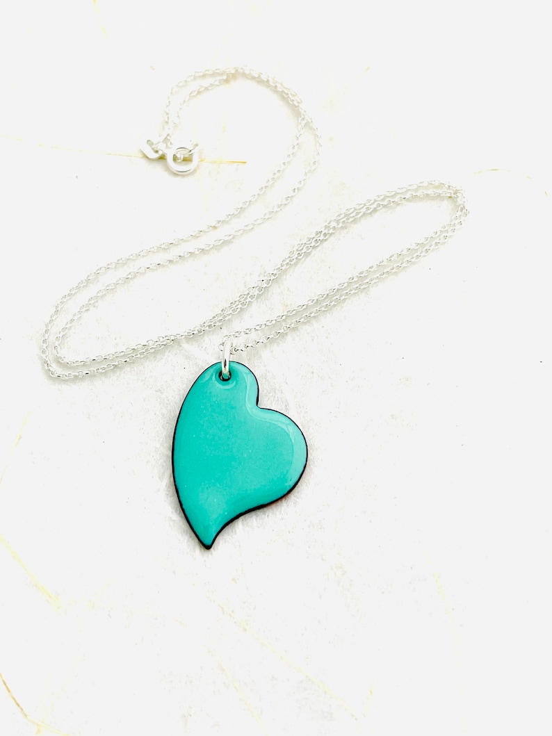 May include: A silver chain necklace with a turquoise blue heart pendant.