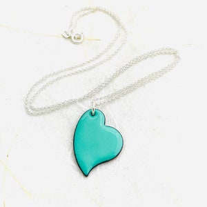 May include: A silver chain necklace with a turquoise heart pendant. The heart is a simple, modern design with a smooth, glossy finish.