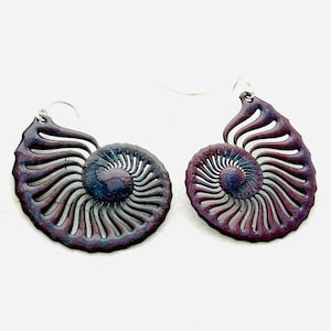 May include: A pair of handcrafted earrings in the shape of a nautilus shell. The earrings are a deep burgundy color with blue accents and silver-colored ear wires. The design features intricate cut-out details.
