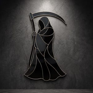 Op de afbeelding: Een glas-in-lood wandhanger die een grimmige maaierfiguur van zwart glas met zilverkleurige metalen soldeerlijnen toont. De figuur is gehuld in een vloeiende mantel en houdt een grote zeis met een gebogen blad boven het hoofd.