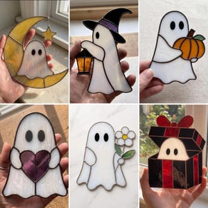 May include: A collection of six stained glass suncatchers featuring white ghosts in various designs: one with a yellow crescent moon and star, a witch with a lantern, a ghost holding an orange pumpkin, a heart, a flower, and a gift box.