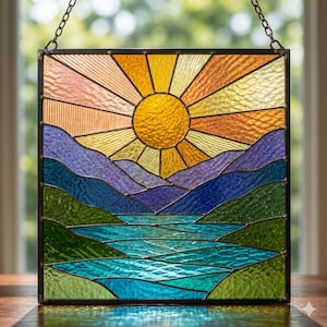 May include: Stained glass panel depicting a landscape with a vibrant sun, mountains, and a river. The sun radiates yellow and orange hues, while the mountains transition from purple to blue. The river is a mix of green and blue.