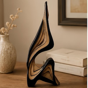 May include: A vertical abstract sculpture composed of layered wood panels with a natural light brown finish and contrasting black painted edges. The structure features curved, flowing lines that create a hollow, organic shape with a pointed top.