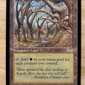 May include: A Gaea's Cradle trading card featuring a brown border and an illustration of a forest with swirling tree trunks. The text reads Legendary Land, Gaea's Cradle, and includes game rules and a quote by Gamelen, Citanul elder, with art by Mark Zug.
