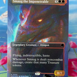 Puede incluir: Una carta coleccionable Smaug the Impenetrable con una ilustración de dragón oscuro e iridiscente con ojos de color naranja brillante. El texto de la carta incluye Legendary Creature - Dragon, Flying, indestructible, haste y 8/7.