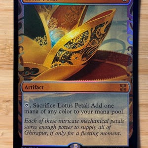 Puede incluir: Una carta coleccionable de Magic: The Gathering titulada Lotus Petal, con una ilustración de una flor mecánica dorada. El texto de la carta dice: Sacrifice Lotus Petal: Add one mana of any color to your mana pool. Es una carta artefacto.