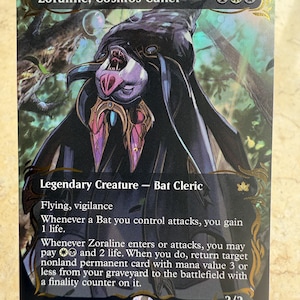 May include: A Zoraline, Cosmos Caller trading card featuring a dark, hooded bat creature with purple accents. The card text includes the name, mana cost, creature type Bat Cleric, abilities, and game rules. The artwork is set against a forest background with gold filigree borders.