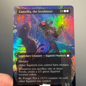 以下が含まれることがあります： 「Camellia, the Seedmiser」と題されたホログラフィック仕様のMagic: The Gatheringトレーディングカード。リスのウォーロックのイラスト、3/3のパワーとタフネス、そしてMenaceやForageといった能力を説明するテキストが、カラフルで反射する仕上げで描かれています。