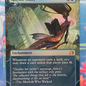 May include: A rectangular Magic: The Gathering trading card titled Rhystic Study. The illustration depicts a dark-skinned merfolk with long flowing hair reading a book underwater. The card text includes the enchantment rules and flavor text.