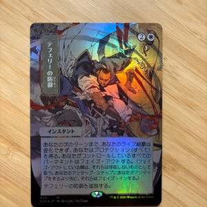 May include: A holographic Magic: The Gathering trading card titled Teferi's Protection in Japanese. The card features a dynamic illustration of a character in blue and white robes with red accents, set against a metallic, reflective foil background.