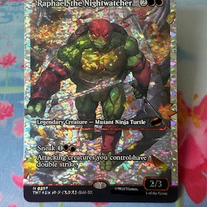 Peut inclure: Une carte à collectionner holographique représentant Raphael, the Nightwatcher, une tortue ninja mutante verte avec un masque et des protège-bras rouges. La carte affiche le texte Raphael, the Nightwatcher, Legendary Creature, Sneak, et Attacking creatures you control have double strike, avec une puissance et une endurance de 2/3.