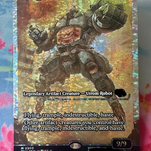 May include: A holographic trading card featuring Krang, Utrom Warlord, a large mechanical robot with a visible brain-like creature in its chest. The card displays the text Krang, Utrom Warlord, Legendary Artifact Creature, and 9/9 power and toughness.