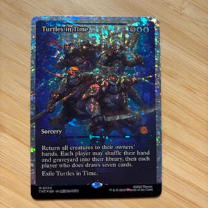 Puede incluir: Una carta coleccionable holográfica titulada Turtles in Time, que muestra cuatro figuras de tortugas con armadura en un entorno azul oscuro. El texto de la carta dice Sorcery, Return all creatures to their owners' hands y Exile Turtles in Time, coste 500.