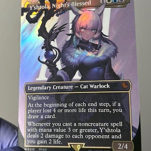 Puede incluir: Una carta coleccionable holográfica de Magic: The Gathering titulada Y'shtola, Night's Blessed. La carta muestra un personaje brujo gato con cabello blanco y atuendo oscuro, sosteniendo un bastón. El texto incluye Legendary Creature, Cat Warlock.