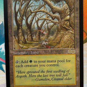 May include: A Magic: The Gathering card titled "Gaea's Cradle." The card features a detailed illustration of a forest with gnarled trees and a small creature. The text includes game instructions and flavor text, with the artist's name at the bottom.