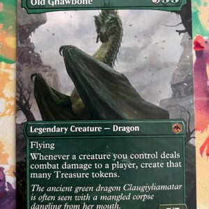 May include: A Magic: The Gathering trading card titled Old Gnawbone, featuring a green dragon illustration. The card text includes Legendary Creature - Dragon, Flying, and combat damage abilities, with a 7/7 power and toughness rating.