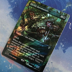 Puede incluir: Una carta coleccionable de Magic: The Gathering titulada Orcish Bowmasters con una ilustración oscura en tonos verdes de dos arqueros orcos. El texto de la carta incluye el tipo de criatura Orc Archer, la habilidad Flash y reglas.