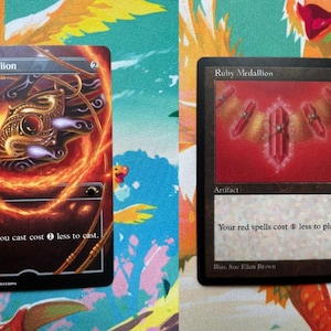 May include: Two Magic: The Gathering trading cards titled Ruby Medallion. The left card features full-art imagery of a golden pendant surrounded by swirling flames. The right card displays a classic border with a red crystal necklace illustration.