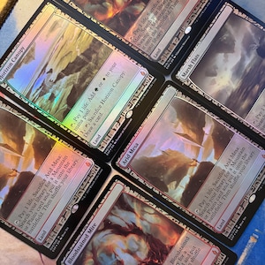 May include: Five Magic: The Gathering trading cards arranged in a fan pattern. The cards include Bloodstained Mire, Horizon Canopy, Marsh Flats, and Arid Mesa. Each card features a holographic foil finish, detailed landscape artwork, and text.